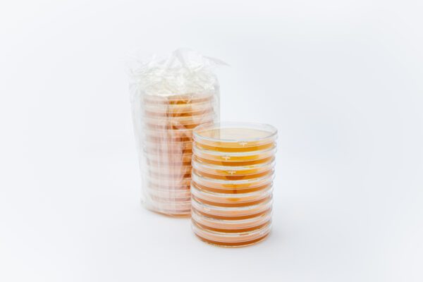 A sealed package of ten 90 mm Surface/Contact Plates – Tryptic Soy Agar (TSA) with eight 90 mm surface/contact plates stacked atop of each other slightly to the front and side of the 10-pack sealed bag of plates.