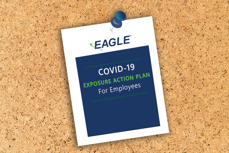 A cork board with a white piece of paper pinned with a blue thumbtack. Text on the sheet says "Eagle COVID-19 Exposure Action Plan For Employees"