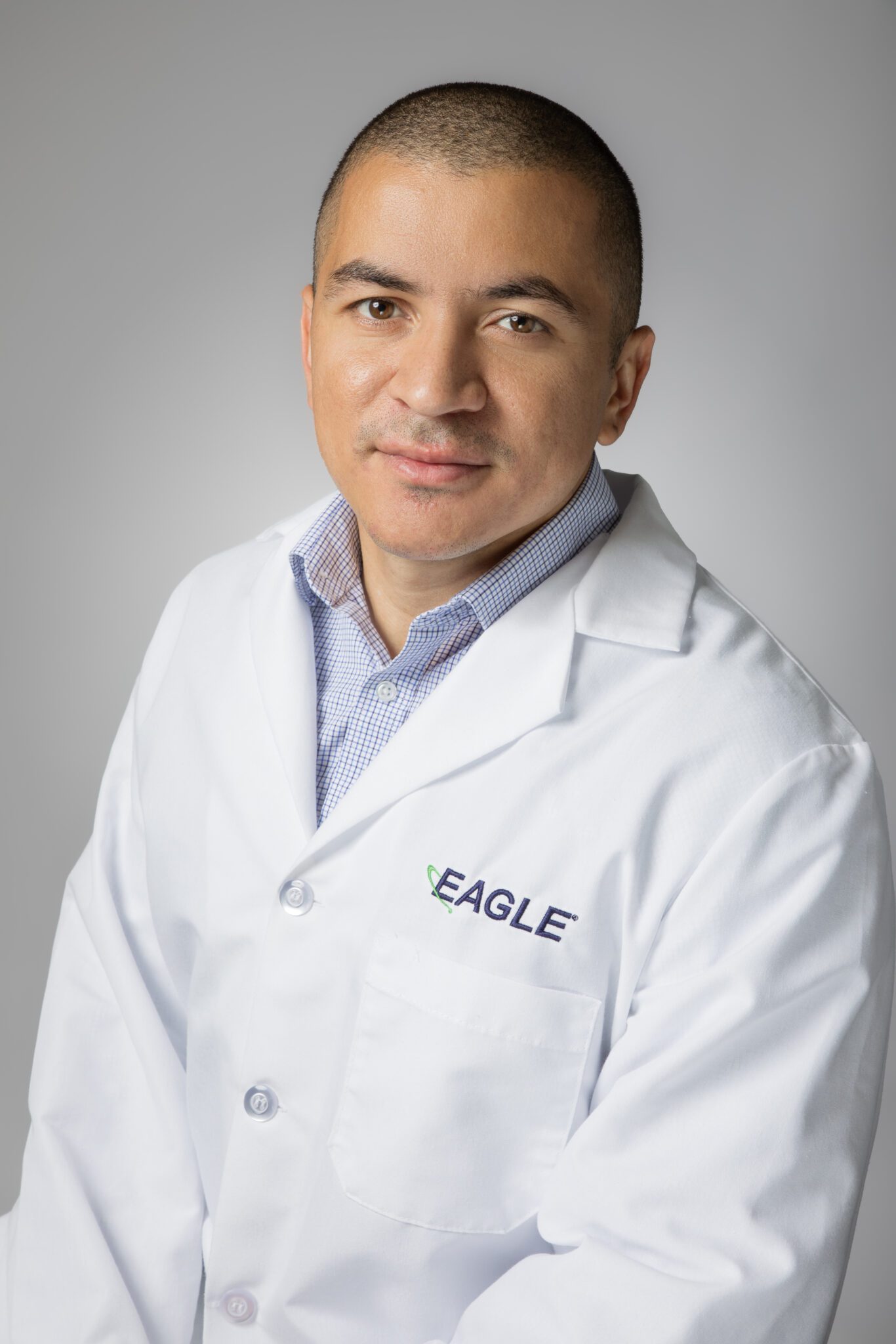 Director of Quality Assurance / Quality Control Manager Miguel Hernandez smiles while wearing a white Eagle lab coat.