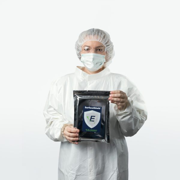 An Eagle employee wearing a lab gown, bennet, facemask and SurfaceShield Wipe Sampling and Cleaning Verification Kit. safety glasses holding a