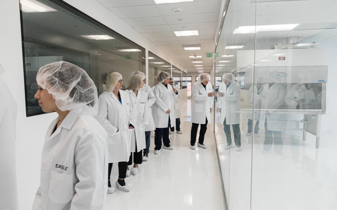An image of PCCA’s Advisory Council #8 touring Eagle's laboratory. The council views through a glass walls housing a cleaning room and other laboratory areas.
